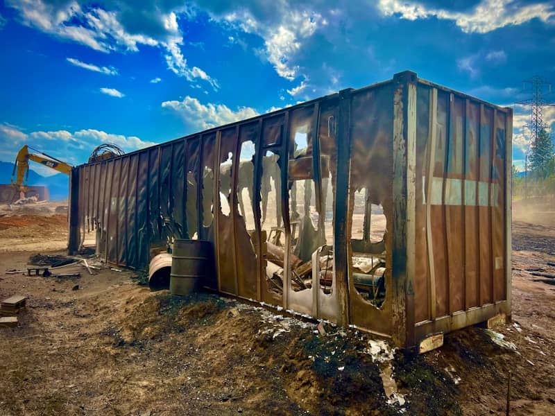The burnt shipping container stands amidst destruction.
